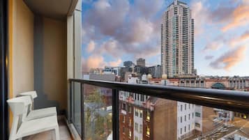 A balcony with a city view, a railing, and a chair.