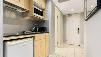 A compact kitchen with a microwave, coffee maker, and a small refrigerator.