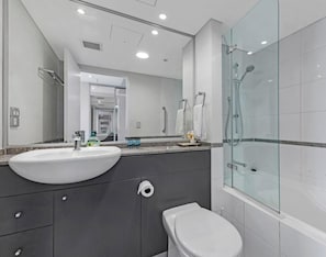 Un bagno moderno con uno specchio grande, un lavandino, un WC e una cabina doccia in vetro.