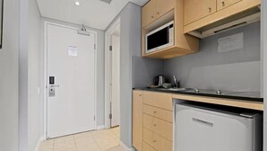 Una cocina compacta con microondas, un refrigerador pequeño y una cafetera sobre la encimera.