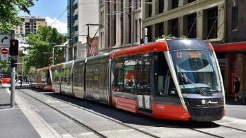 A modern tram with the number 12 on its front, traveling on a track in an urban setting.