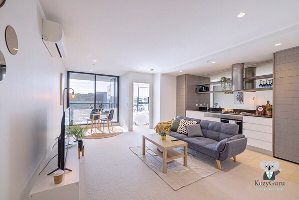 A modern apartment with a living room, dining area, and kitchen.