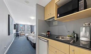 Une chambre d’hôtel équipée d’une kitchenette, d ’un lit, d’un bureau et offrant une vue sur la ville.