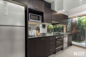 A modern kitchen with dark cabinetry, a stainless steel refrigerator, a microwave, a gas stove, and a dishwasher.
