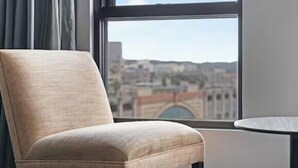 Une chaise placée près d’une fenêtre, avec vue sur le paysage urbain.