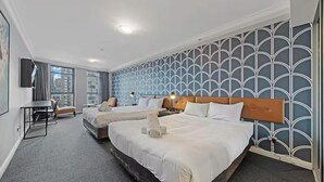 Une chambre d’hôtel avec deux lits, un bureau, une chaise et une grande fenêtre.