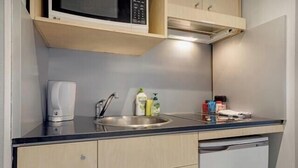 Une cuisine compacte équipée d’un four à micro-ondes, d’un évier et d’un lave-vaisselle.
