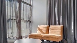 A modern room with a sofa, a round table, and sheer curtains. - KozyGuru | Sydney CBD | Best Location Studio (Haymarket)