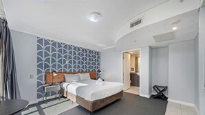 A modern hotel room with a bed, bedside table, lamp, and a patterned wall. - KozyGuru | Sydney CBD | Best Location Studio (Haymarket)