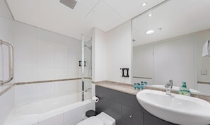 Une salle de bain moderne avec une douche Ă parois de verre, un lavabo blanc et un grand miroir.