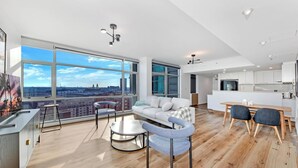 Una sala de estar moderna con un gran ventanal, un sofá, una mesa de centro y un comedor con sillas.