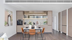 A modern kitchen with a dining area, featuring a central island, built-in appliances, and a view of the city. - Haymarket Prime Location Charming 2 Bed (Haymarket)
