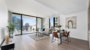 A modern living room with a city view, a dining area, and a large window. - Haymarket Prime Location Charming 2 Bed (Haymarket)