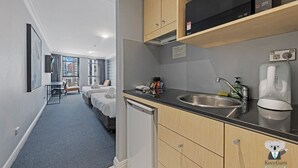 Ein modernes Hotelzimmer mit Küchenzeile, großem Fenster und Blick auf die Stadt.