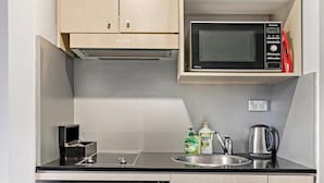 Una kitchenette compacta con microondas, pileta y alacenas.