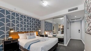 Una habitación de hotel moderna con una cama grande, mesitas de noche, un espejo y un papel tapiz estampado.