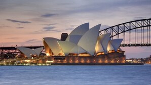 La Casa de la Ópera de Sydney, con su diseño distintivo de velas, situada junto al Puente de Sydney.