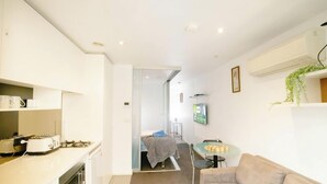 Un espacio habitable compacto con kitchenette, comedor y dormitorio.