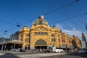 Ein großes, historisches Gebäude mit einer markanten Kuppel und einem Rundbogenportal, umgeben von modernen Gebäuden und belebten Straßen.