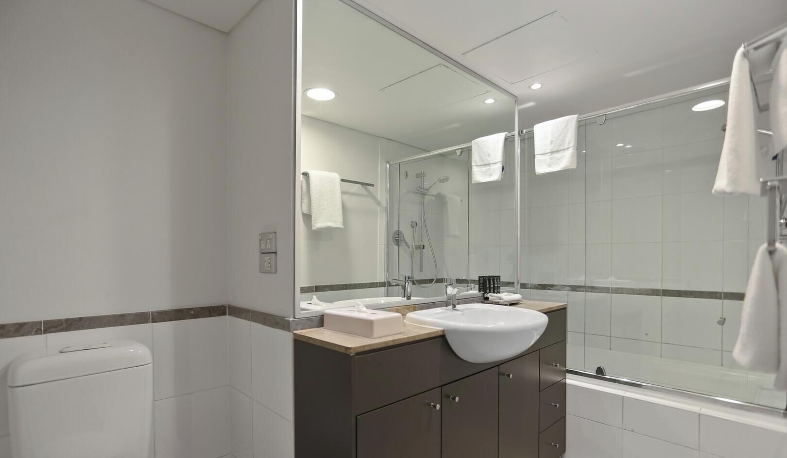A modern bathroom with a glass shower enclosure, a double sink vanity, and a toilet.