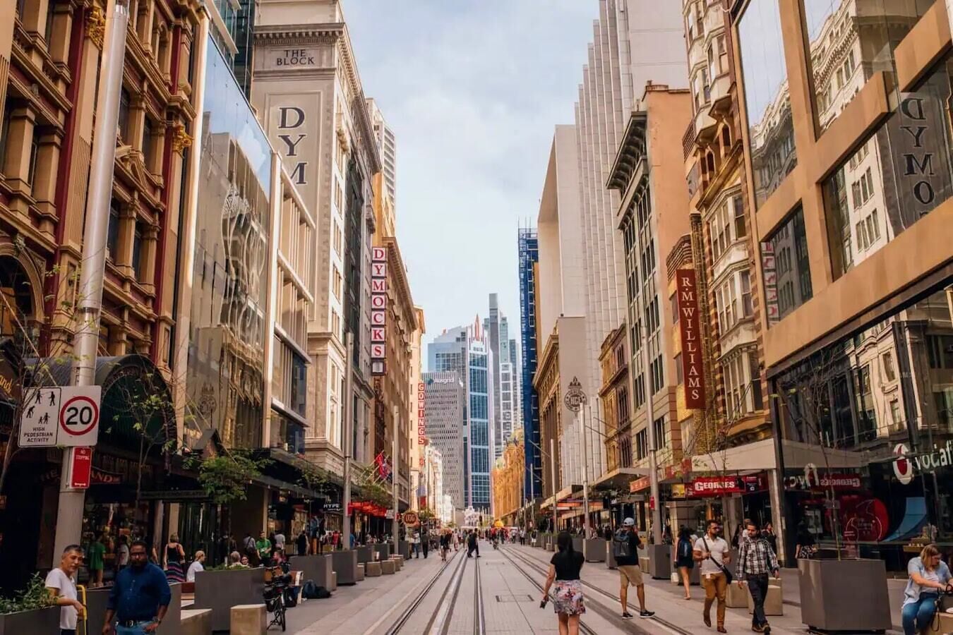 A street with historic buildings, a tram, and pedestrians.