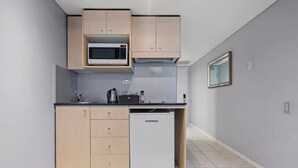 A compact kitchen with a microwave, cabinets, and a dishwasher. - KozyGuru | Haymarket | Bright City Studio (Haymarket)