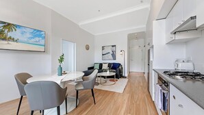 Una cocina moderna con estufa a gas, un comedor con mesa y sillas, y una sala de estar con sofá y mesa de centro.