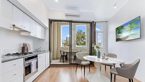 Una cocina moderna con zona de comedor, ventanas amplias y un cuadro en la pared.