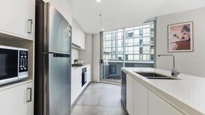 A modern kitchen with stainless steel appliances, a dishwasher, and a large window providing natural light.
