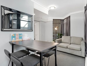 Relax in a spacious room with a large mirror, dining table, and comfortable sofa.