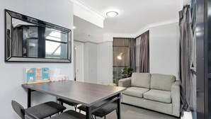 Una sala moderna con un sofá, una mesa de comedor con sillas, un espejo grande y una lámpara.