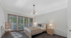 A bedroom with a bed, bedside tables, a chair, a window with blinds, and a ceiling light fixture.