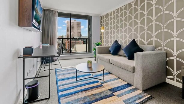 A modern living room with a sofa, a coffee table, and a dining area.