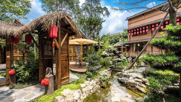 Un jardin de style japonais traditionnel, avec un sentier de pierres, un petit étang et des constructions en bois.