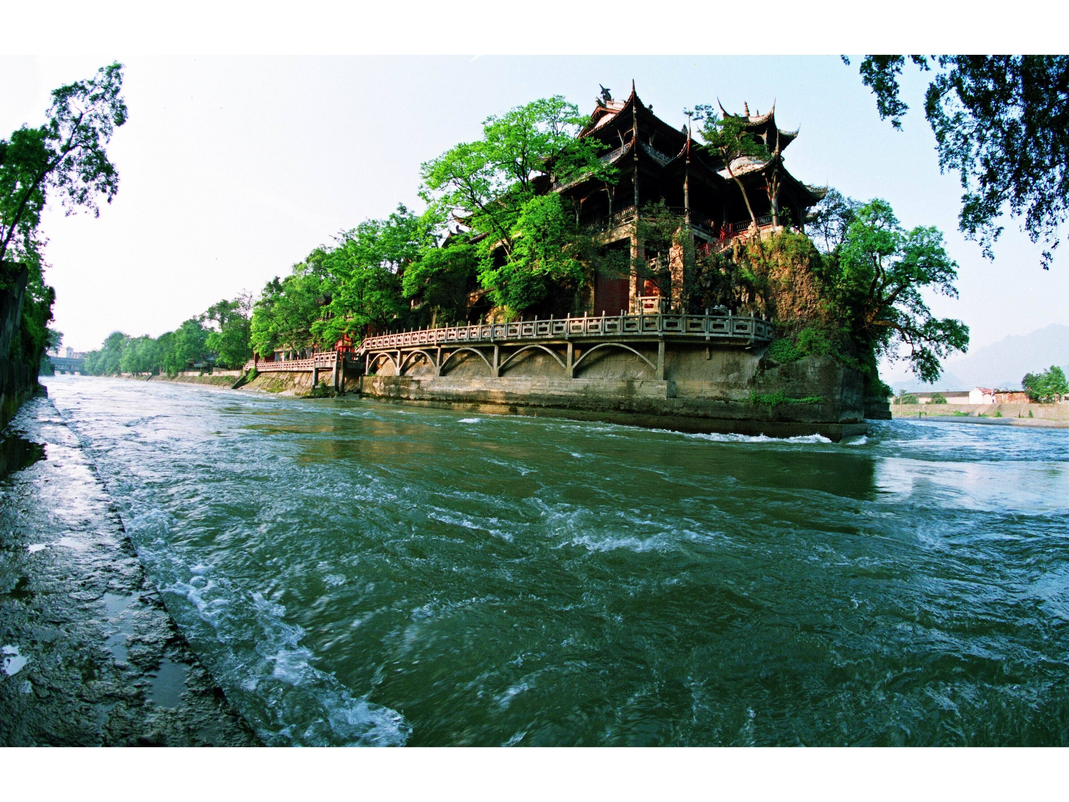 A traditional multi-tiered building with a bridge over a river.