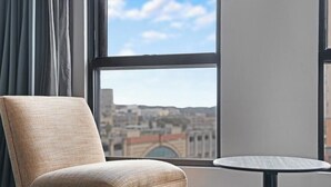 Ein Zimmer mit großem Fenster, einem Sessel und einem kleinen Tisch.