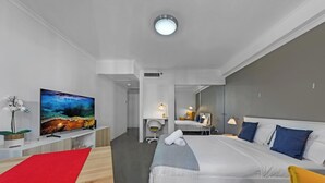 Ein modernes Hotelzimmer mit Bett, Fernseher, Schreibtisch und Bad.