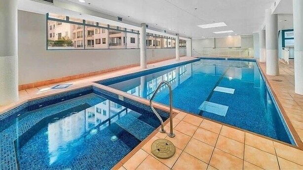 Ein Hallenbad mit großen Glaswänden, gefliestem Boden und modernem Design.