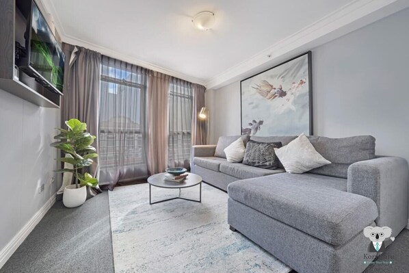 A modern living room with a grey sofa, a coffee table, and a potted plant.