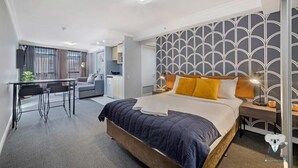 A modern hotel room with a bed, bedside table, and a desk area.