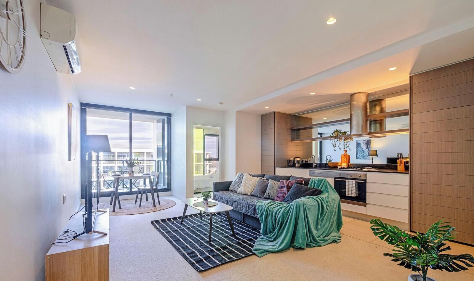 Un apartamento moderno con comedor, sofá, cocina y un ventanal grande.