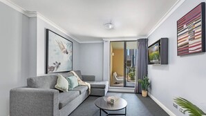 Ein modernes Wohnzimmer mit einem grauen Sofa, einem Couchtisch und einer Glastür, die auf einen Balkon führt.