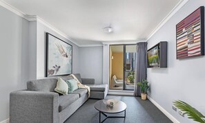 A modern living room with a grey sofa, a coffee table, and a sliding glass door leading to a balcony.