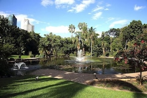 Ein Park mit Teich, Brunnen und Palmen.