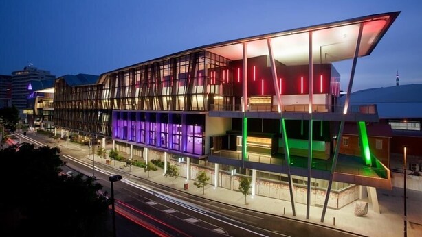 Een modern gebouw met een glazen gevel en kleurrijke verlichting.