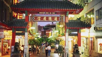 A traditional Chinese gate with a sign, surrounded by shops and pedestrians.