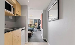 A narrow hallway leading to a balcony with a bed and a small table.