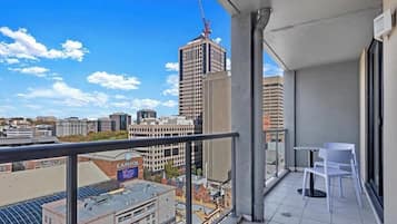 A balcony with a view of a cityscape, including a tall building under construction, a sign for Capital One Bank, and a clear blue sky.