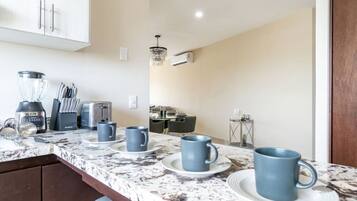 A kitchen with a marble countertop, a coffee maker, a toaster, and a chandelier.