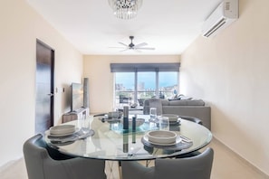 A modern dining area with a glass table, chairs, and a city view.